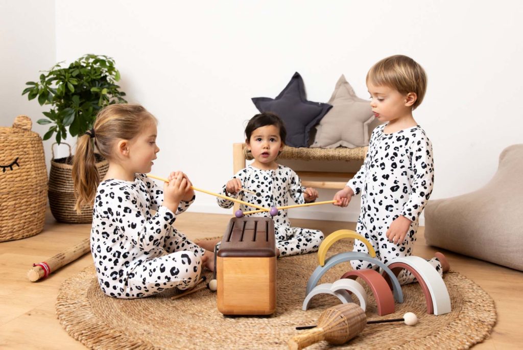 Trois très jeunes enfants autour d'une sorte de xylophone