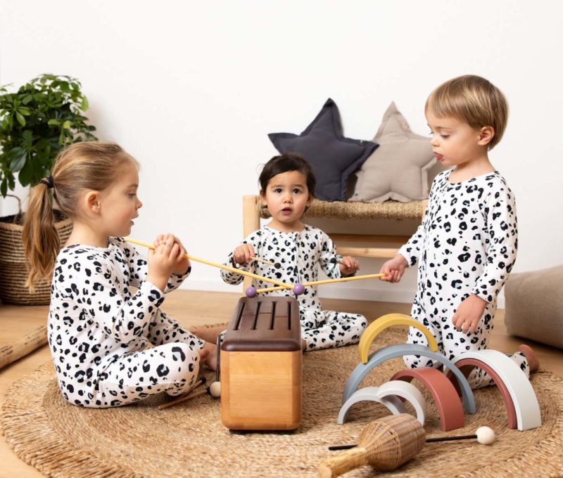 Trois très jeunes enfants autour d'une sorte de xylophone