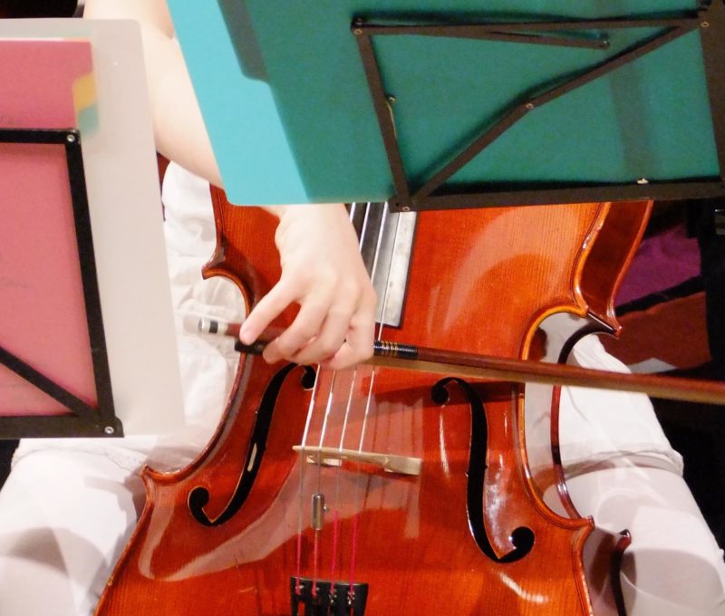 Photo d'un enfant jouant du violoncelle : gros plan sur le violoncelle et l'archet