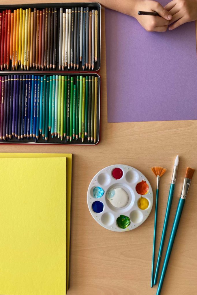 Crayons de couleur, palette, pinceaux, papier coloré