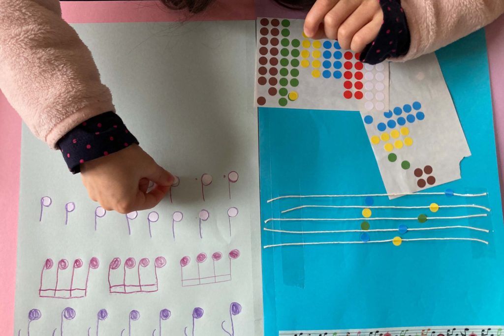 mains d'enfant collant des gommettes sur des notes de musique