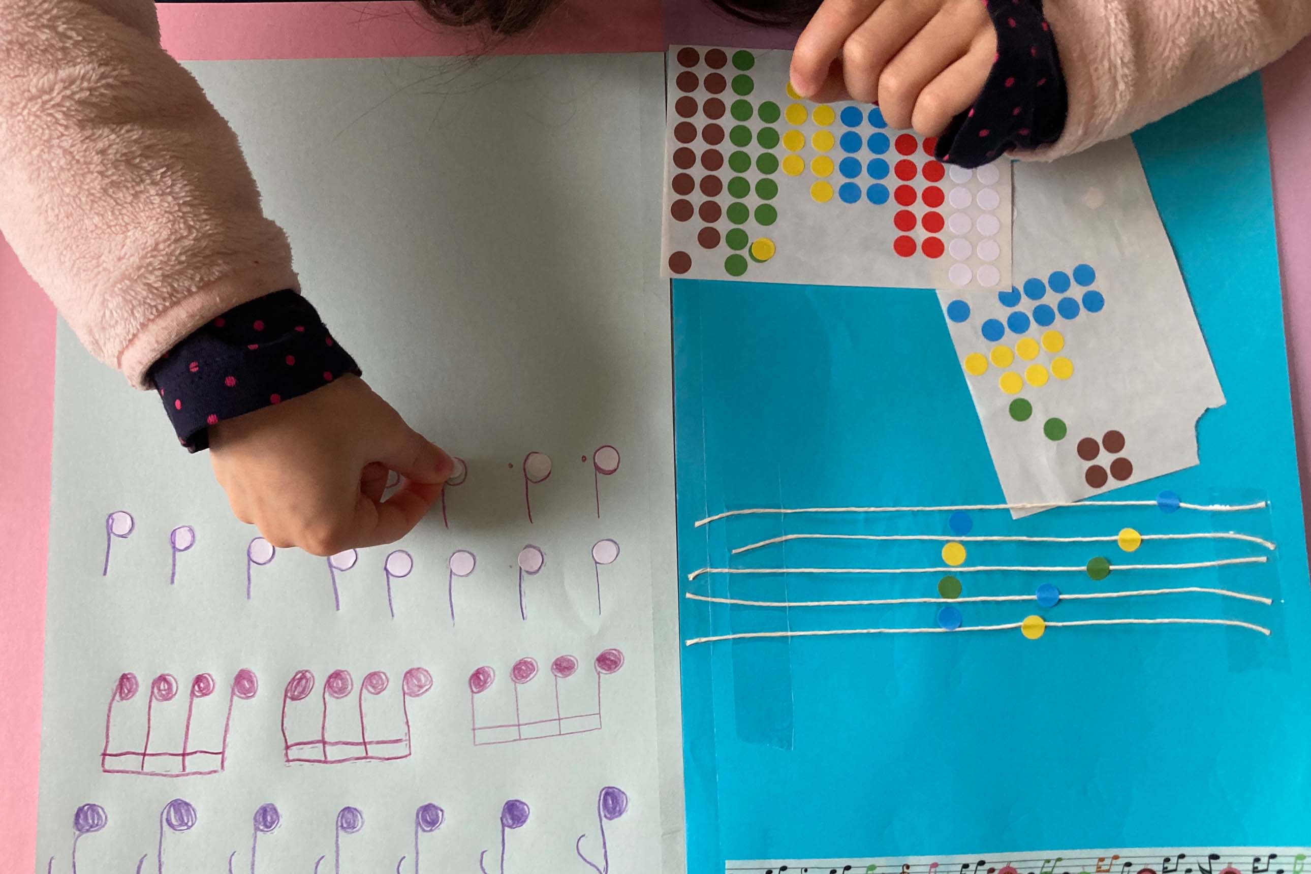 mains d'enfant collant des gommettes sur des notes de musique
