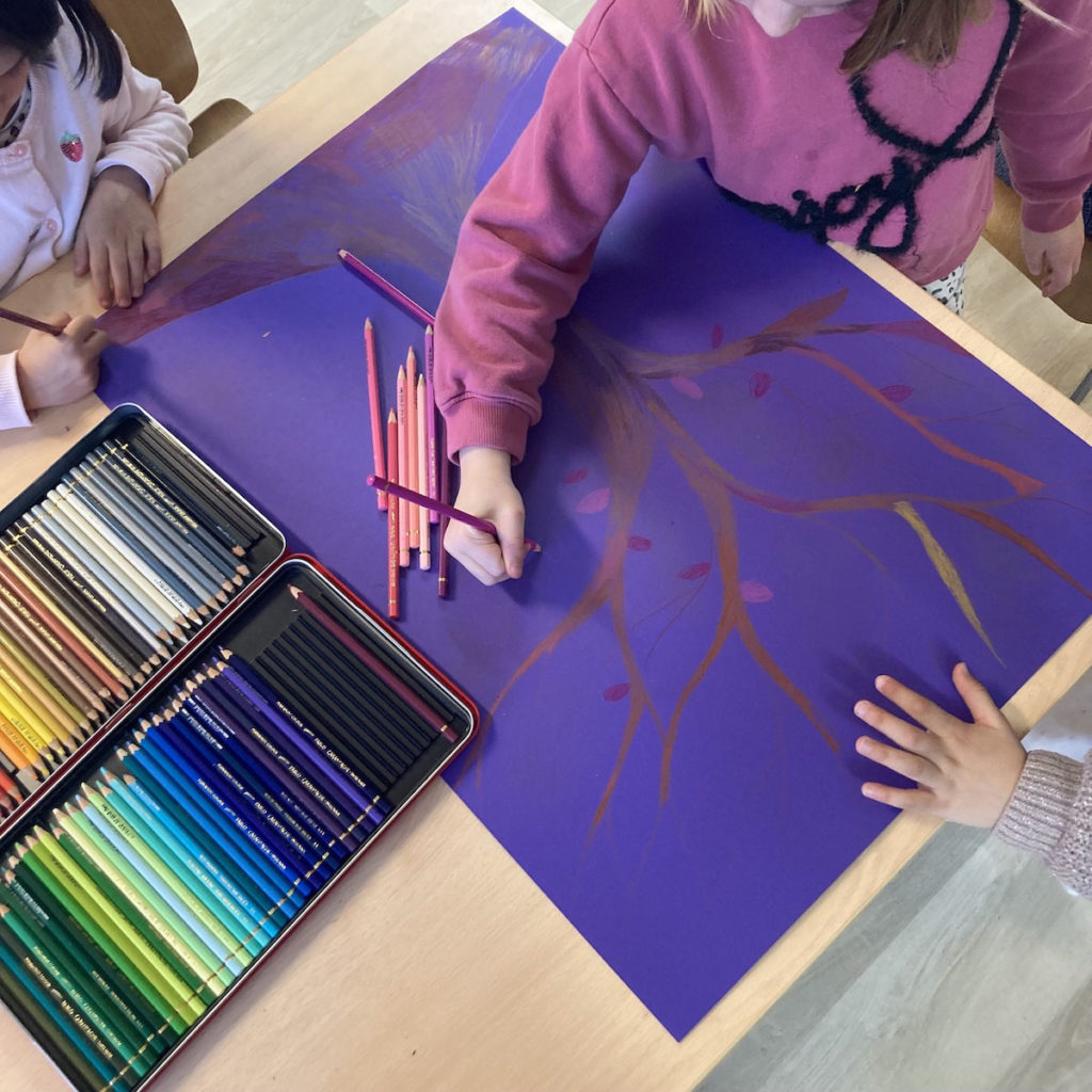 Gos plan sur un dessin d'arbre sur fond violet, 3 enfants dessinent sur le même dessin