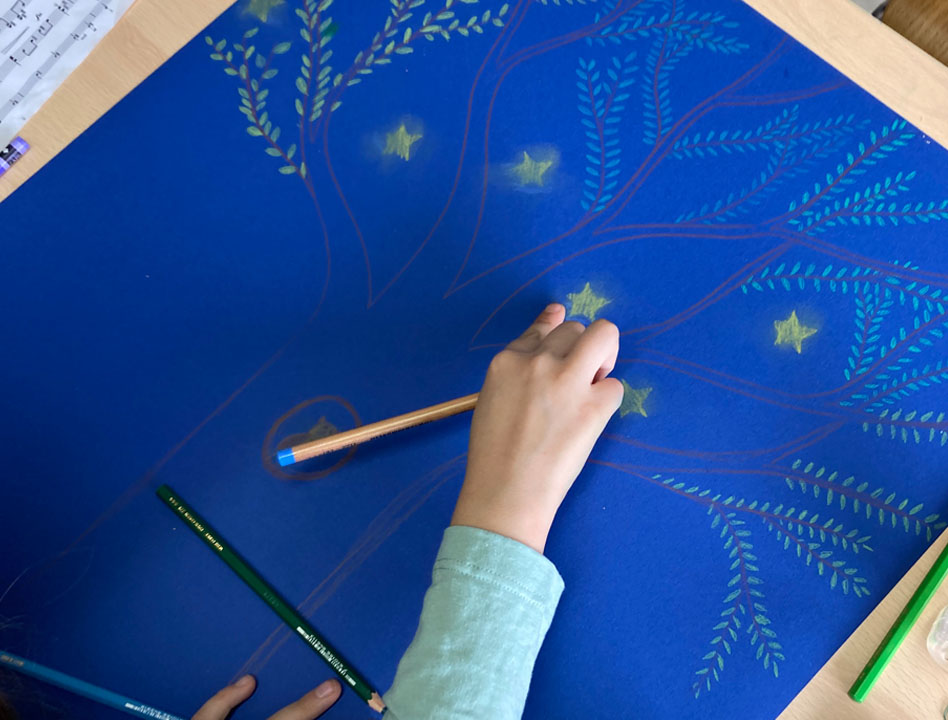 grand dessin d'arbre sur fond bleu foncé, main d'enfant en train de dessiner