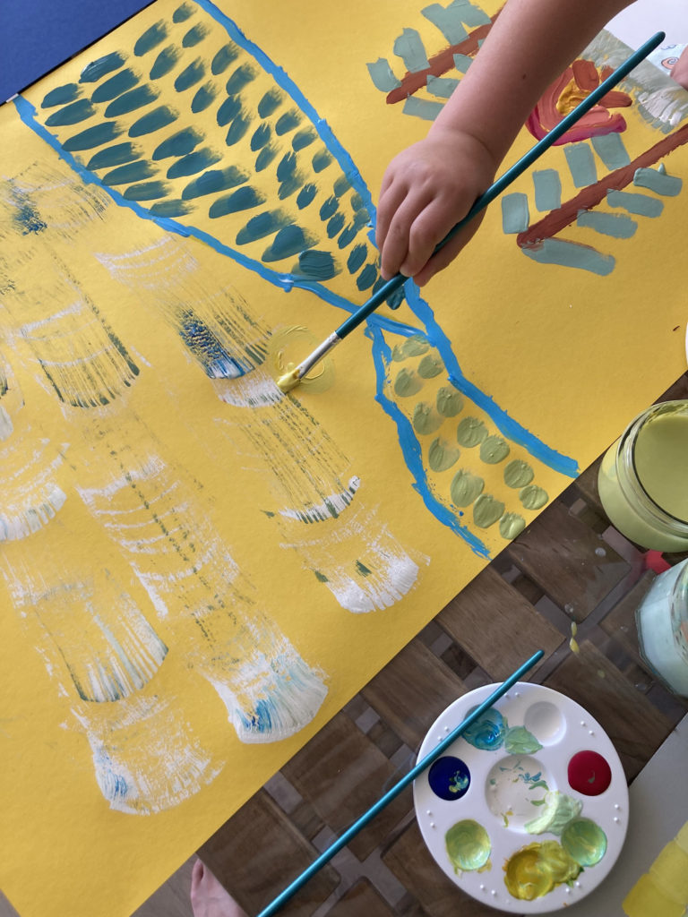 gros plan sur un enfant dessinant un paysage sur une grande feuille jaune