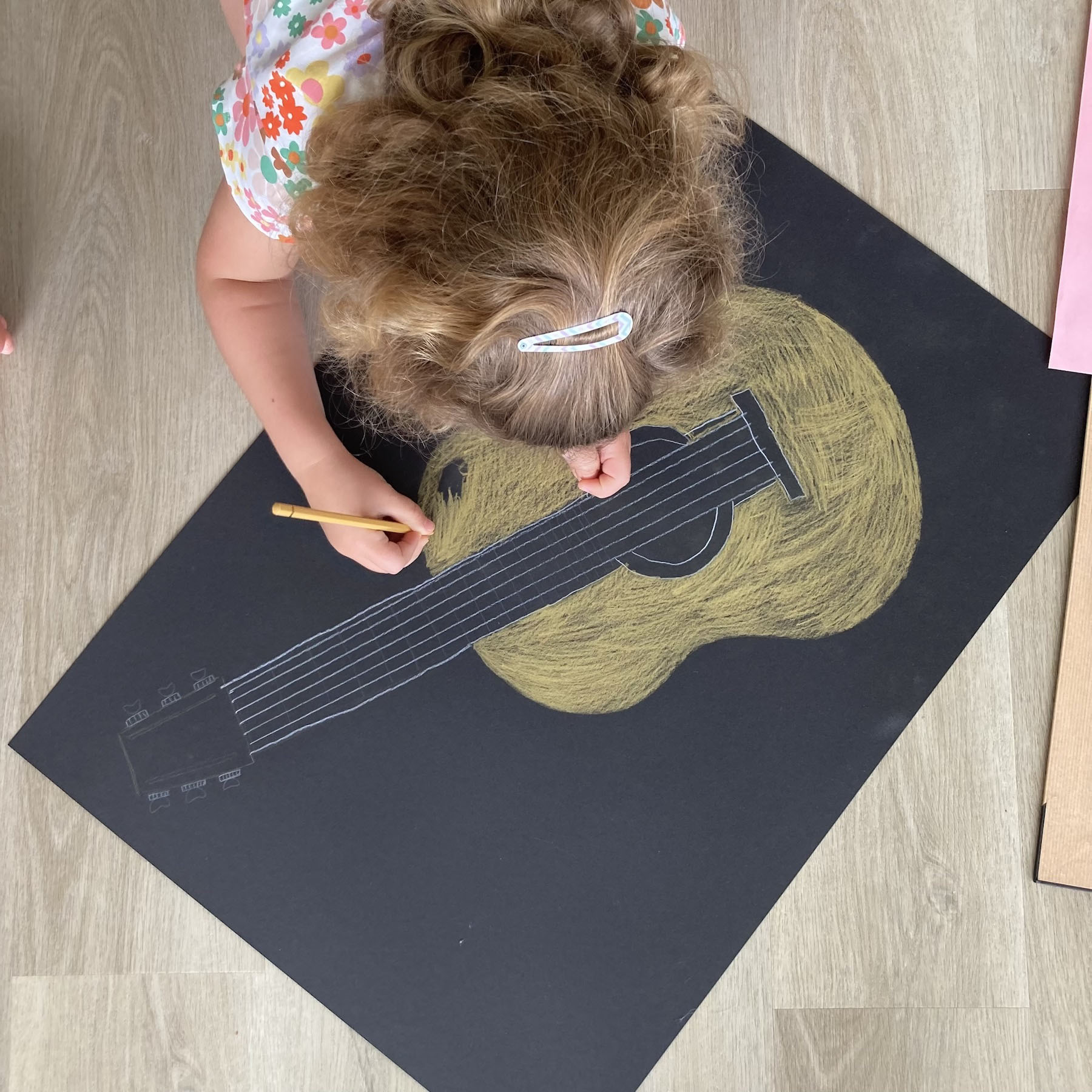 Enfant dessinant une guitare grandeur nature, vue de dessus