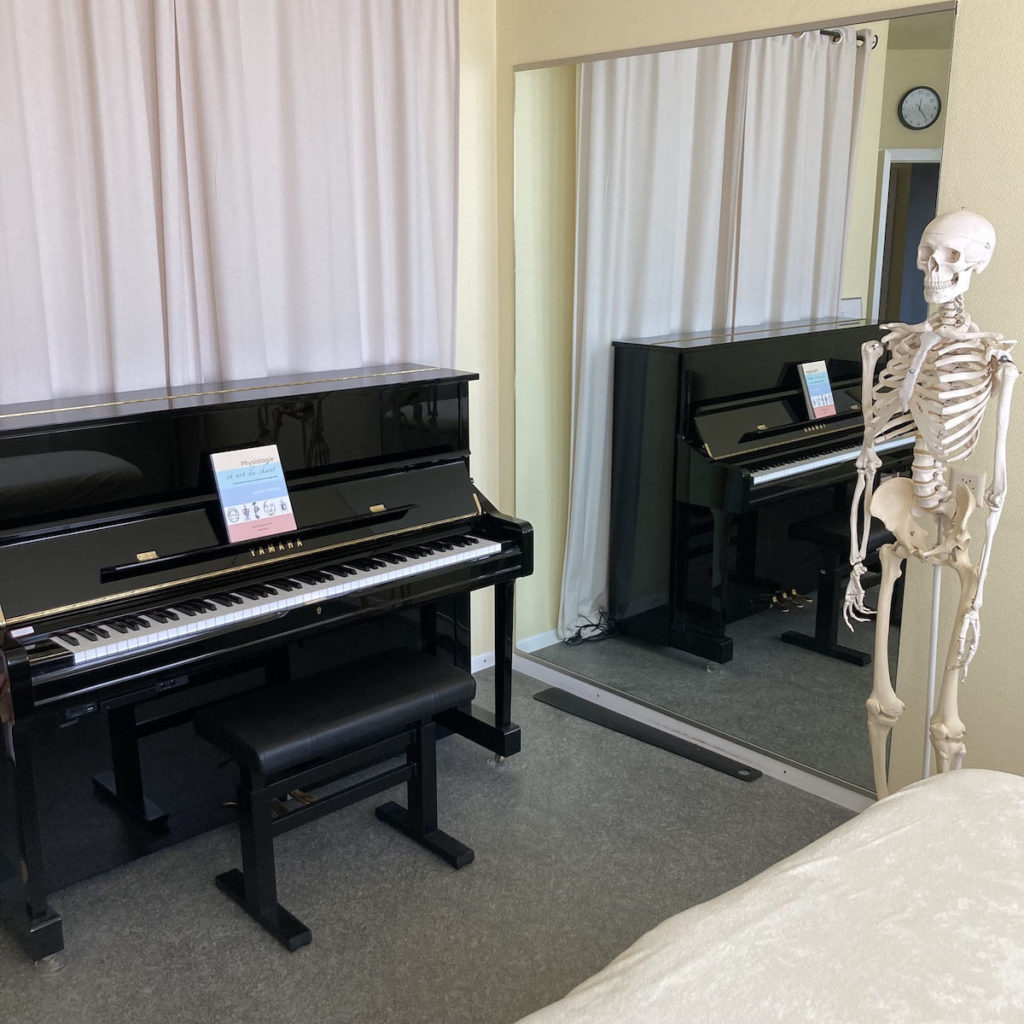 salle de soin d'un cabinet de physiothérapie pour musiciens : piano droit, miroir, squelette