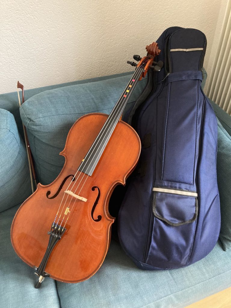 violoncelle d'enfant avec archet et housse, posés sur un canapé