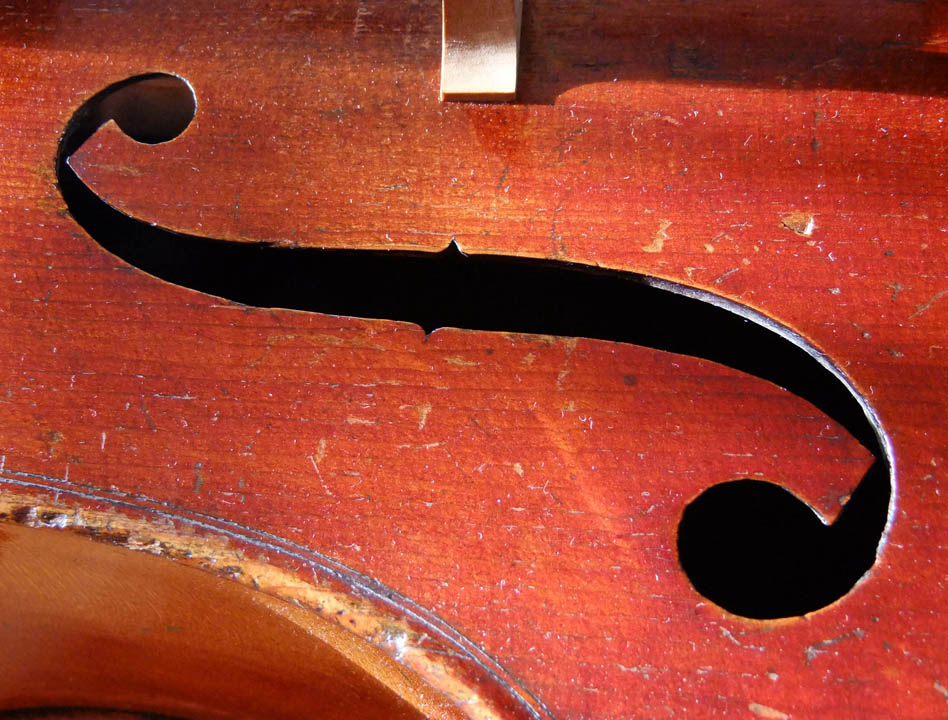 gros plan sur l'ouïe d'un violoncelle ancien, au vernis rouge