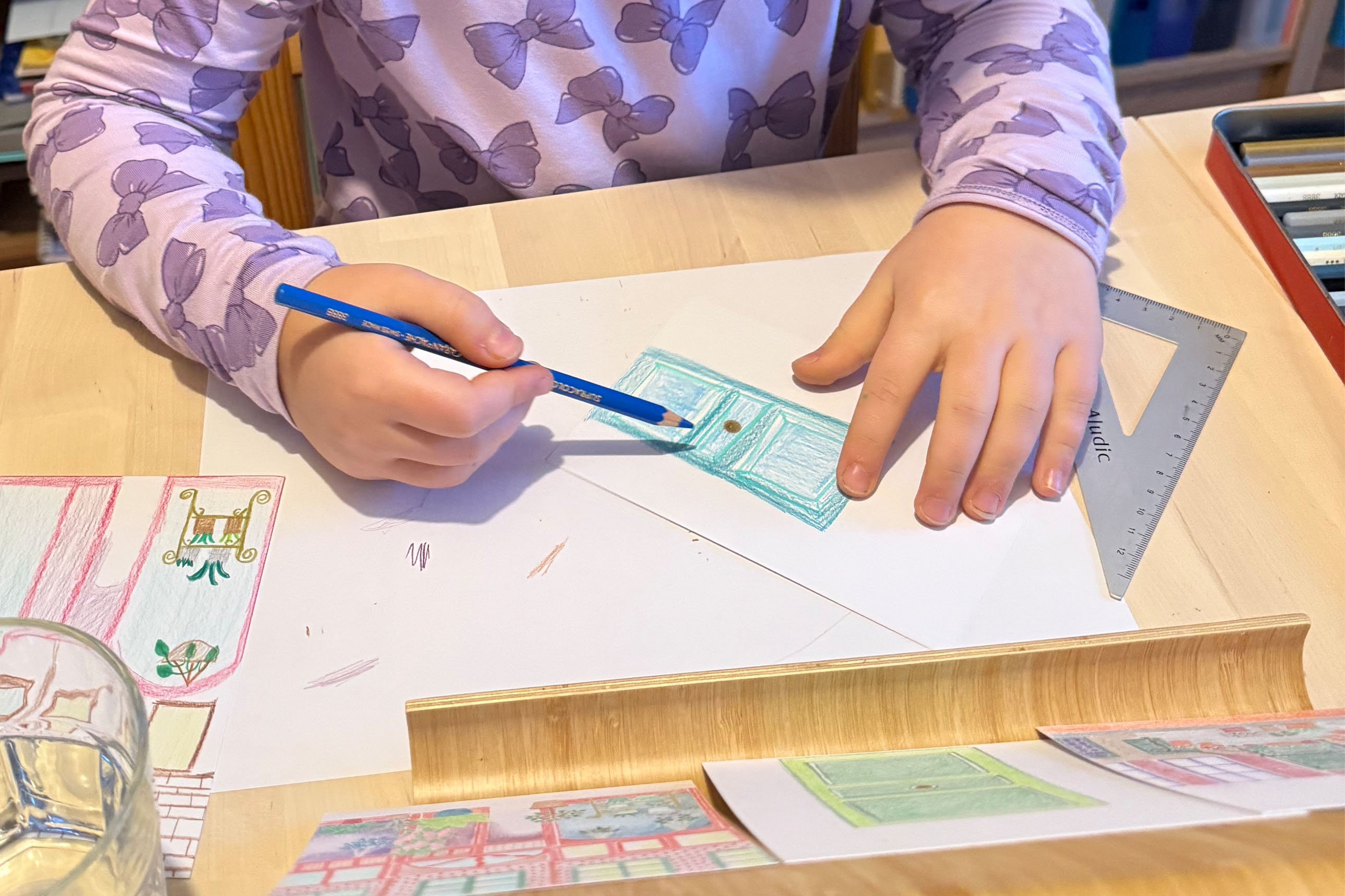gros plan sur un enfant qui dessine une porte, avec un crayon bleu