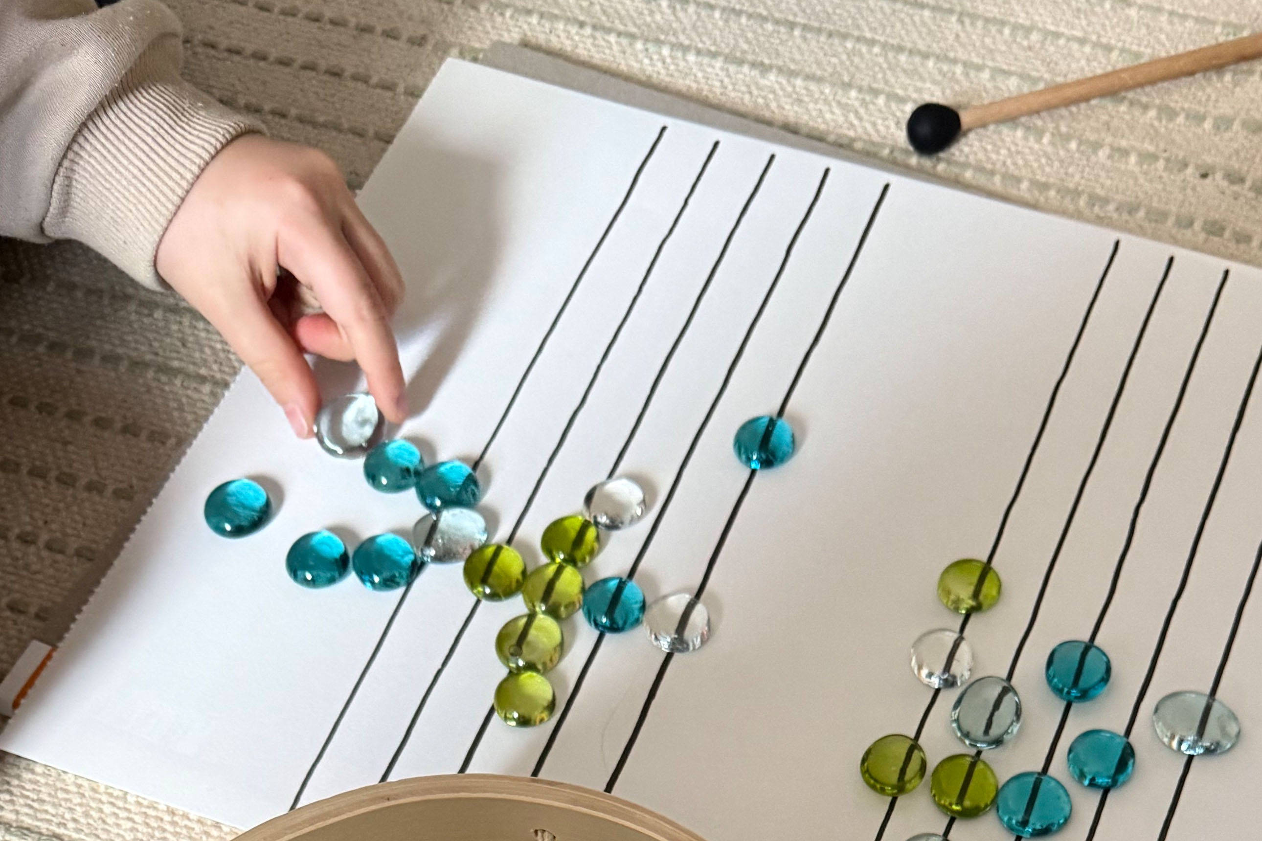 gros plan sur main d'enfant disposant des billes en verre plates sur des portées musicales