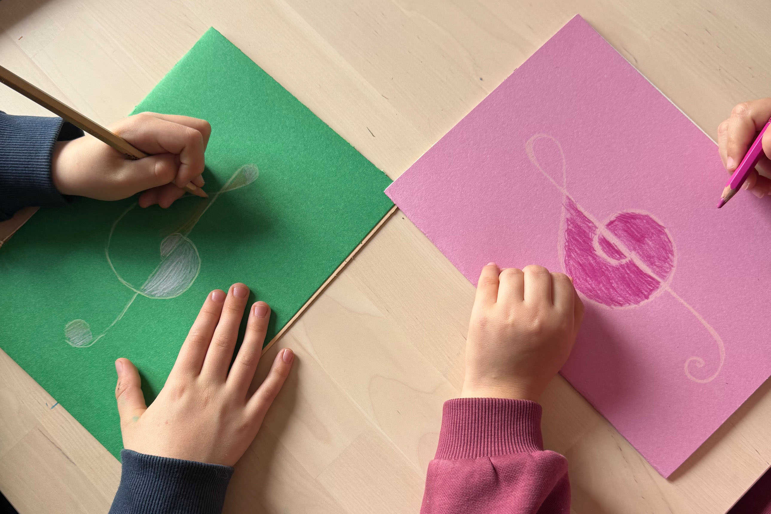 gros plan sur des mains d'enfant coloriant des clés de sol sur papier coloré