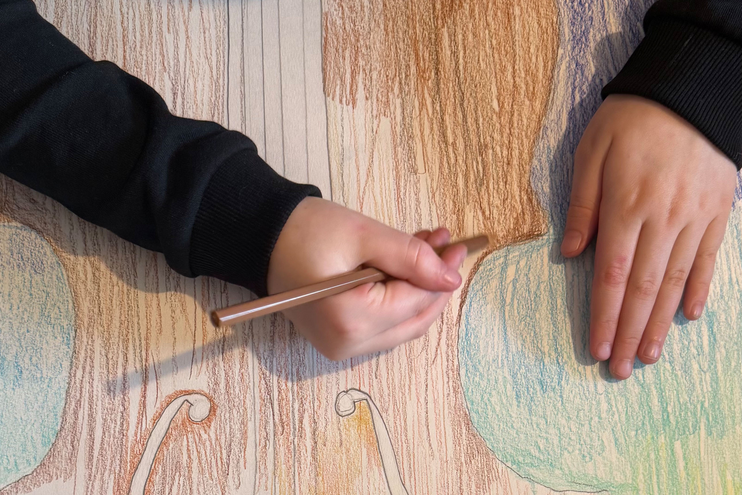 gros plan sur les mains d'un enfant dessinant un violoncelle
