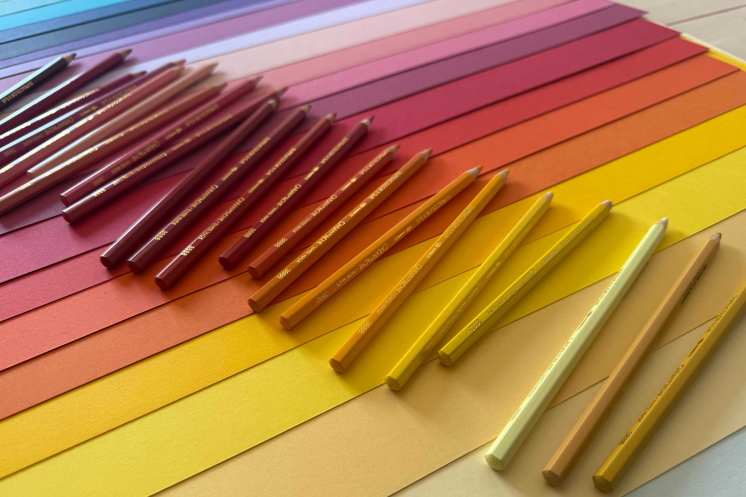 crayons de couleur en dégradé jaune-rose sur papiers des mêmes couleurs