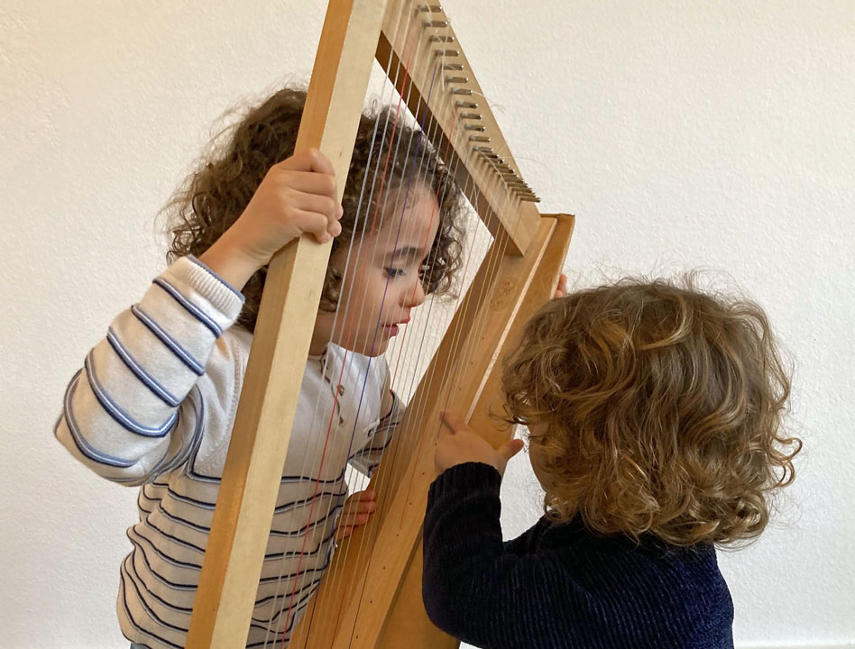 deux enfants essayant une petite harpe